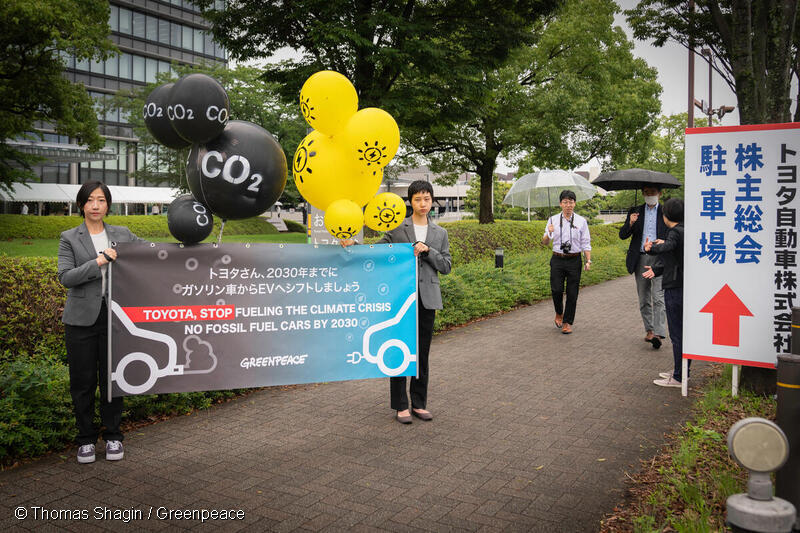 トヨタ本社前で「2030年までにガソリン車からEVへシフトしましょう」と書かれたバナーとバルーンを掲げ、グリーンピースからトヨタへのメッセージをアピールするグリーンピースメンバー