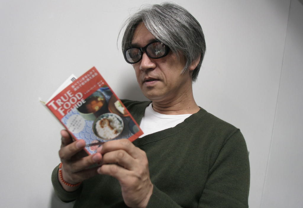 食についての本を読む坂本龍一さん