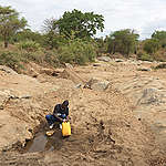 A man collects water at an almost completely dried up well in Tharaka Nithi County. This is the only well used by all the villagers nearby to collect water. The drought is visible in the surroundings.