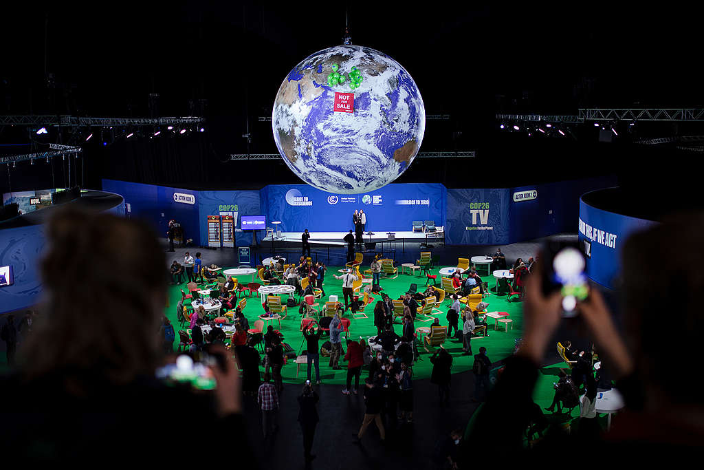 Greenpeace activists raise a banner reading “NOT FOR SALE” against the iconic giant globe at the centre of the COP26 conference hall in Glasgow, as talks enter their final hours. © Emily Macinnes / Greenpeace