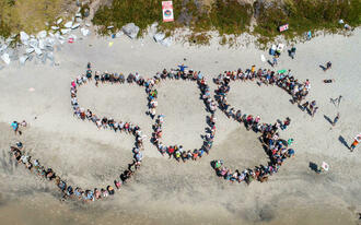 An aerial view of people on a beach spelling out SOS