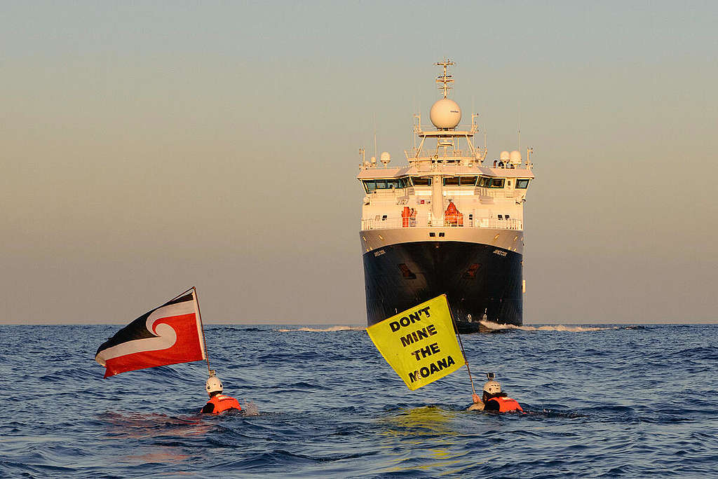 From the Greenpeace ship Arctic Sunrise, Greenpeace International activists confront the UK Royal Research ship MV James Cook in the East Pacific waters as it returned from a seven-week long expedition to a section of the Pacific Ocean targeted for deep sea mining. A Greenpeace activist scaled the side of the moving vessel to unfurl a banner reading “Say No to Deep Sea Mining”, while two Māori activists swam in front of the James Cook, one holding the Tino Rangatira flag and the other a flag reading “Don’t Mine the Moana”.