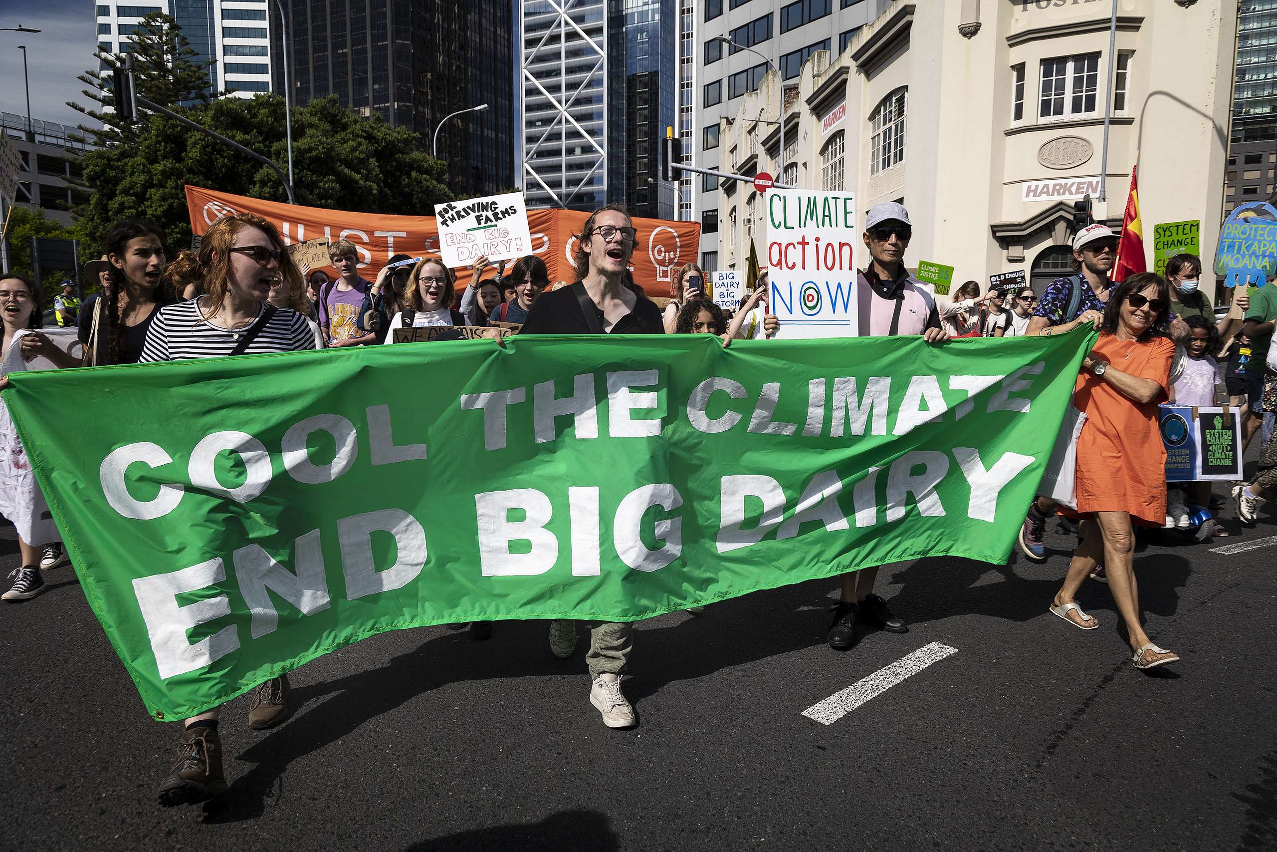 People walk behind a green banner that says Cool the climate, End big dairy