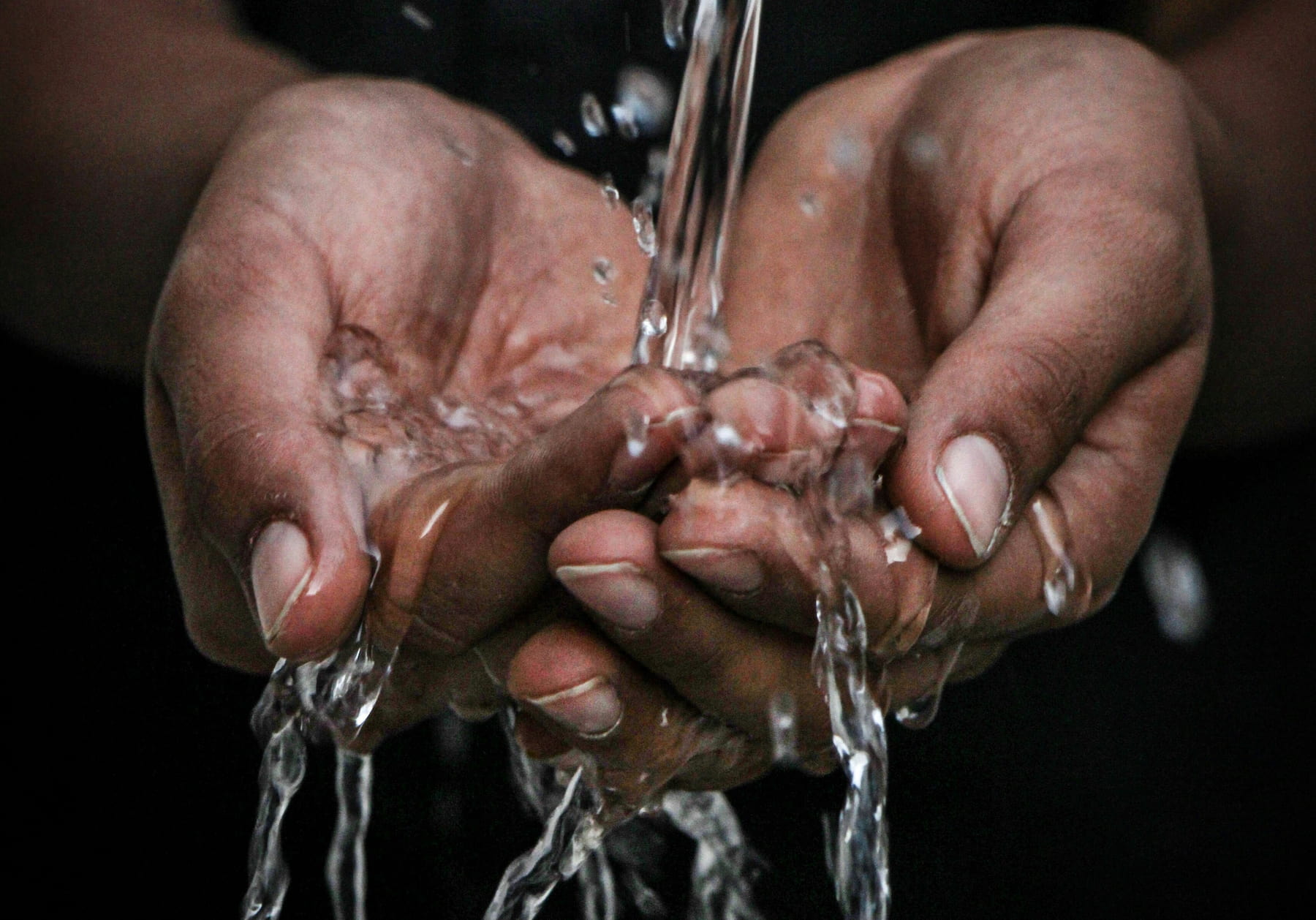 Water splashing from a tap onto clasped hands