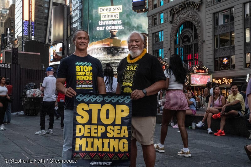 Hawaiian elder, cultural advocate and former statesman, Solomon Pili Kahoʻohalahala (right) and Hawaian cultural advocate Ekolu Lindsey (left) stand beneath a large LED video billboard in Times Square put up by Greenpeace USA to expose the threat of Deep Sea Mining and urge people to help stop the destructive industry before it starts.