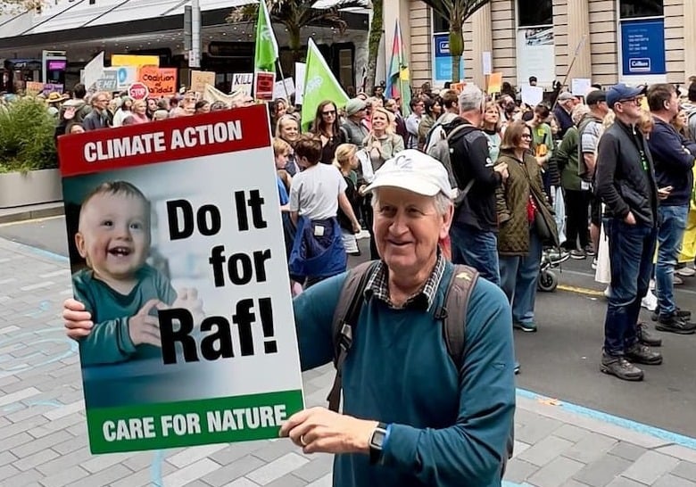 Gord Stewart with a placard featuring his grandson Raf and the message Clmiate Action, Do it for Raf, Care for Nature