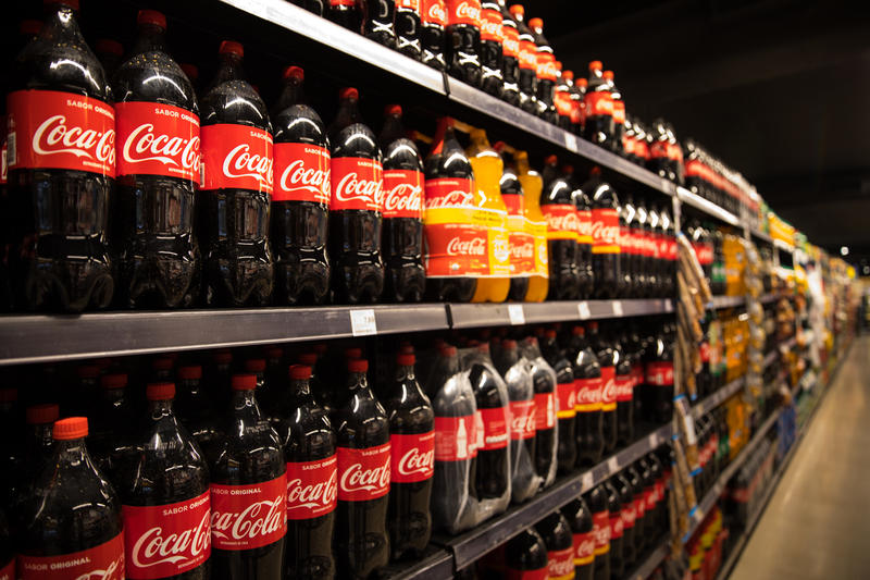 A row of Coca Cola 2L plastic bottles on supermarket shelves