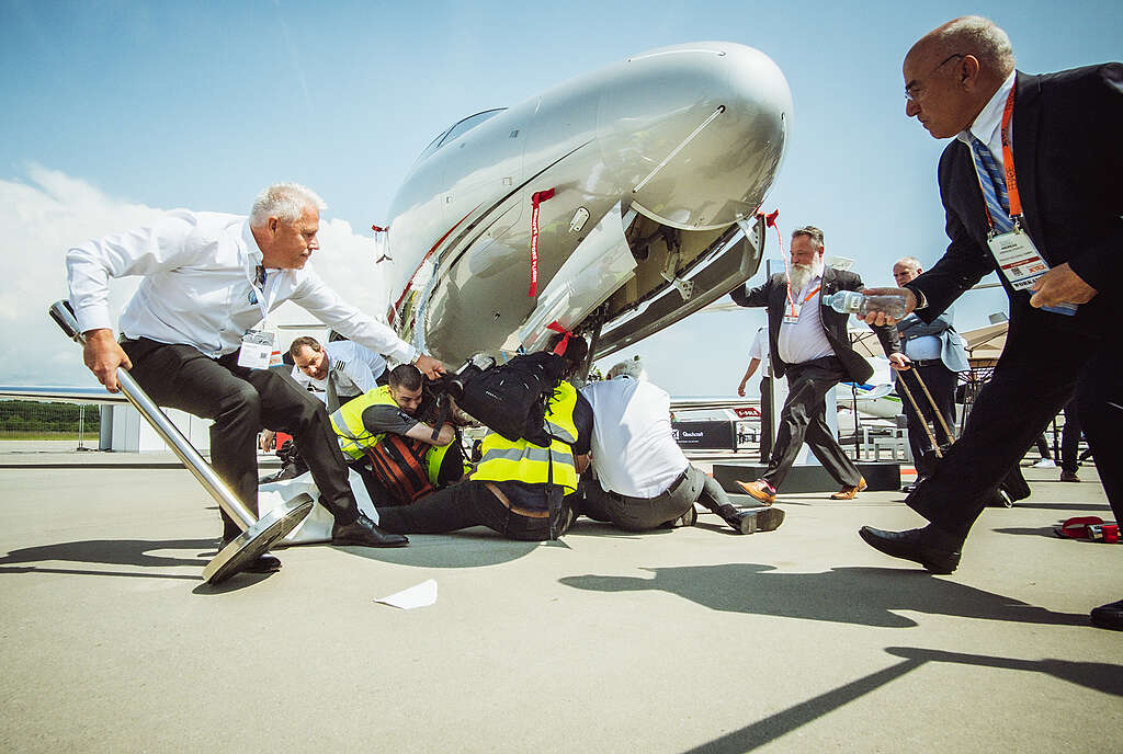 Los activistas ocupan pacíficamente los aviones privados expuestos en el evento empresarial del aeropuerto de Ginebra, encadenándose a las pasarelas de los aviones y a la entrada de la exposición para impedir la entrada a posibles compradores.