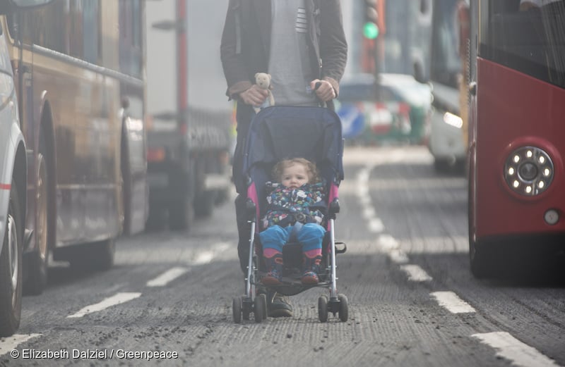 Un niño pequeño es empujado en un cochecito por una calle muy transitada en Londres.