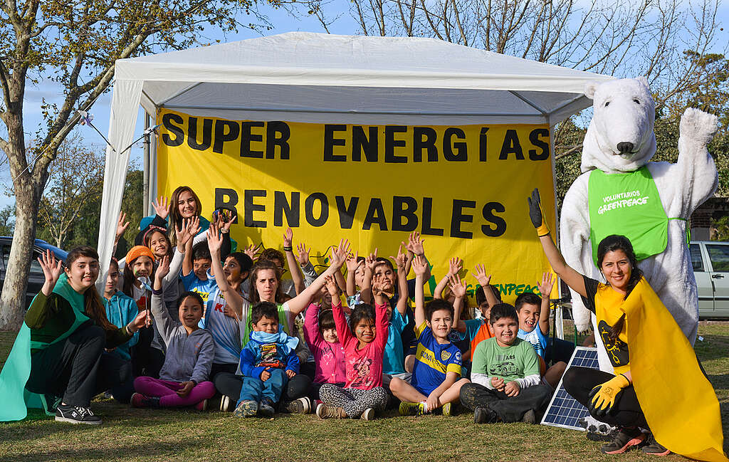 Voluntarios de Greenpeace en Bahía Blanca participan en un acto con una pancarta que dice: 'Super Energias Renovables'.
