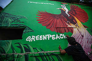 Artista de rua pinta o nome do Greenpeace em mural com aves do paraíso na Indonésia.