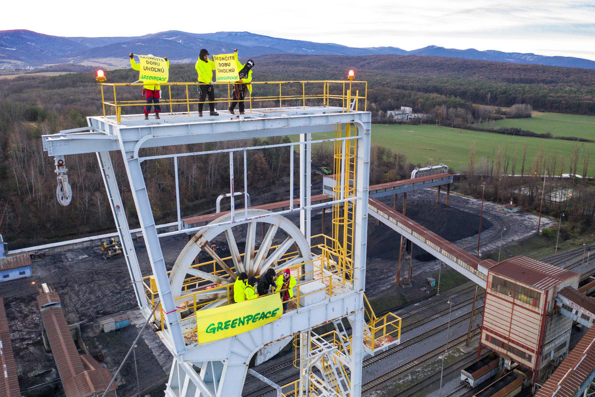 Ativistas do Greenpeace seguram um banner em uma torre de uma mineradora