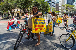 Cicloativista segura placa com os dizeres "Com dificuldade para respirar? Chega de emissões", na Avenida Paulista