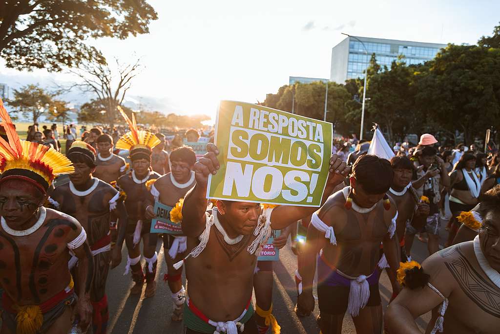 Foto de indígenas no Acampamento Terra Livre em 2023 segurando o banner ''A resposta somos nós!'' 