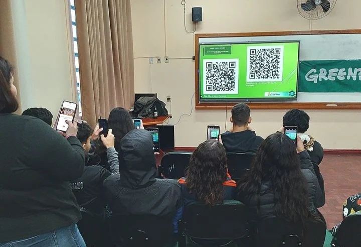 Foto de estudantes que apontam seu celular para o QR code com petições do Greenpeace