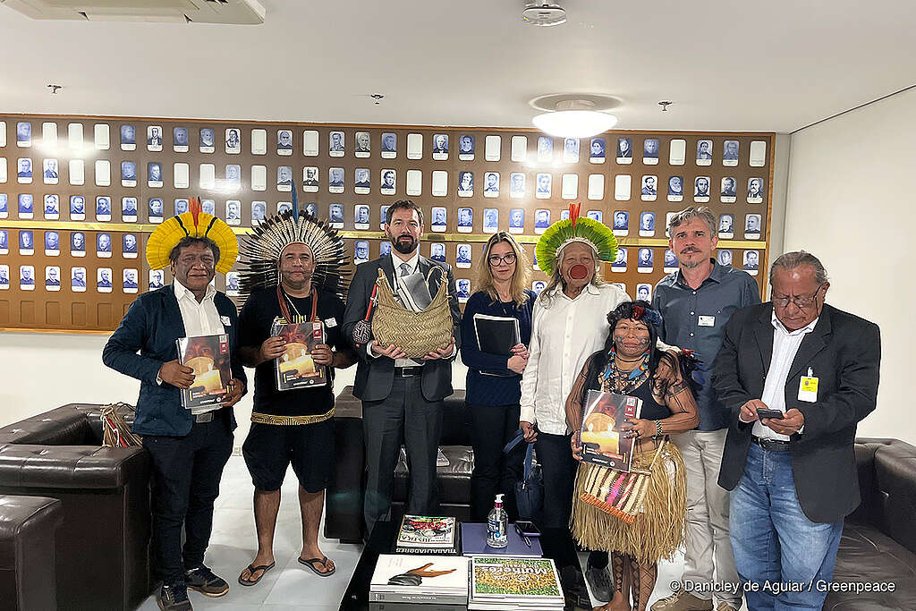 Lideranças indígenas, ativistas da APIB (Articulação dos Povos Indígenas do Brasil) e do Greenpeace Brasil reunidos em uma sala entregando uma petição de rejeição ao Marco Temporal ao Supremo Tribunal Federal em Brasília. 