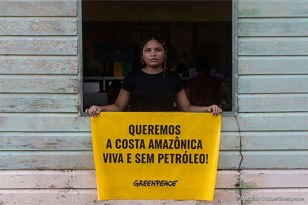 Garota em uma janela segurando banner com a frase: “Queremos a costa Amazônica Viva e sem petróleo”