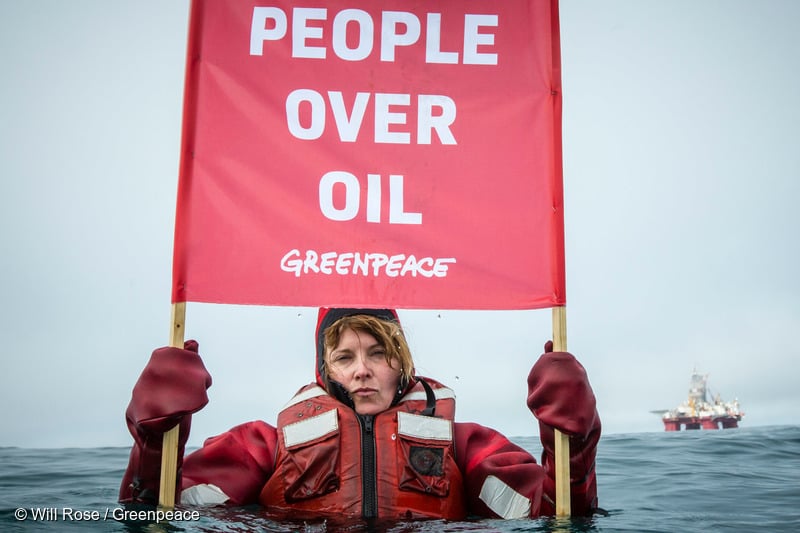 Луси Лоулес държи банер с надпис „Хората над горивата“. © Will Rose / Greenpeace