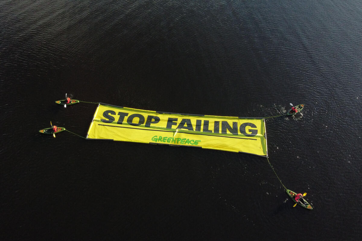 Greenpeace UK Kayakers with floating banner "Stop Failing". © Kristian Buus / Greenpeace
