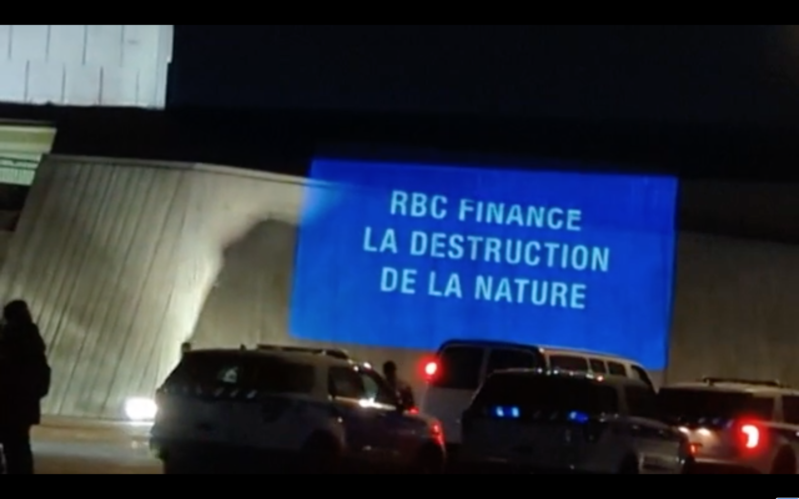 Projection en pleine soirée qui dit "RBC finance la destruction de la nature"