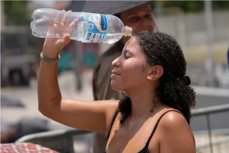 Mujer se refresca el rostro utilizando una botella con agua.
