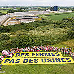 An aerial view of the protest against the Avel Vor farm, where volunteers unfurl a 35-metre-long banner reading "Farms not factories" in the meadow near the farm in Landunvez.
Other banners were unfurled in several messages to highlight the deleterious consequences of the hog farming such as "Mega-slaughterhouses =mega-pollution", "Factory farms = polluted water + air", the need to put an end to it ("Stop factory farms", "Factory farms no thanks") and to defend "Farming without agro-industry".  

The participants then strolled through the streets of Landunvez, in a festive but determined manner, in the form of an animal carnival to symbolise farm animals.
Dans une prairie proche de l’exploitation Avel Vor, les militants et militantes ont déroulé une banderole géante de 35 mètres de long sur laquelle est écrit : “Des fermes pas des usines”. D’autres banderoles ont été déployées pour rappeler les conséquences délétères de l’élevage industriel (“Méga-porcheries = méga-pollutions”, “Fermes-usines = eau + air pollués”), la nécessité d’y mettre fin (“Stop fermes-usines”, “Fermes-usines non merci”) et de défendre “Une paysannerie sans agro-industrie”. Les participants ont ensuite déambulé dans les rues de Landunvez, de manière festive mais déterminée, sous forme de carnaval des animaux pour symboliser les animaux d’élevage.