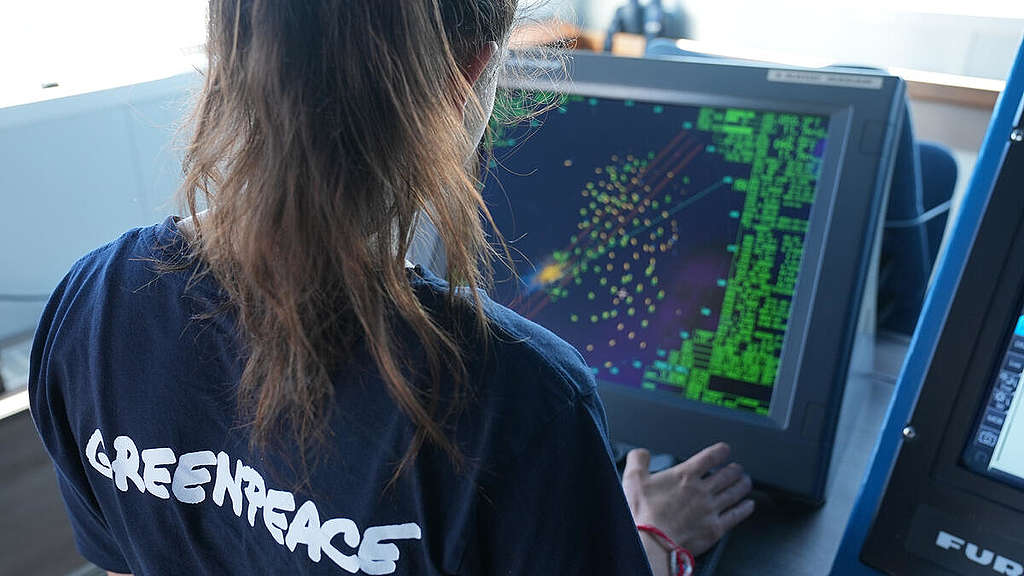 Greenpeacen tiimin jäsen tutkii tutkaa, jossa näkyy satoja kalastusaluksia.