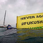 Greenpeace divers display a banner reading “Never again” during sampling operations off the coast of Fukushima Daiichi nuclear plant, Japan. The action is carried out in occasion of the approaching 5th anniversary of the Fukushima nuclear disaster. The Greenpeace ship Rainbow Warrior is in the background.