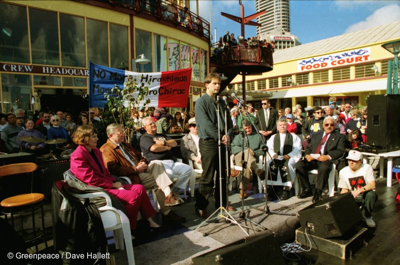 Michael Szarbo addresses crowd from stage. Michael Szabo of Greenpeace joins PM Jim Bolger and opposition leaders at public rally as a flotilla of small yachts leave Auckland bound for Moruroa to protest against French nuclear tests at the atoll.
