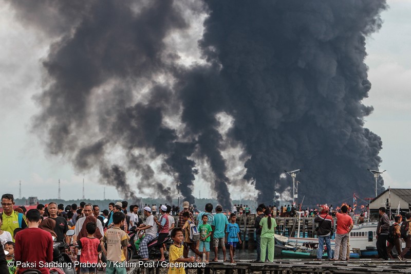 Residents watch a fire from the oil spill in Balikpapan bay, East Kalimantan. An oil spill off Borneo island that led to five deaths and the declaration of a state of emergency was caused by a bursed of undersea pipe belongs to Indonesia's state oil company Pertamina