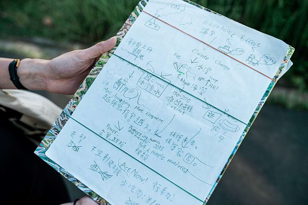 Lance用硬皮圖書、橡筋做成環保文件夾，有聯署書、綠色投書還有他手作的氣候信息圖。© Patrick Cho / Greenpeace