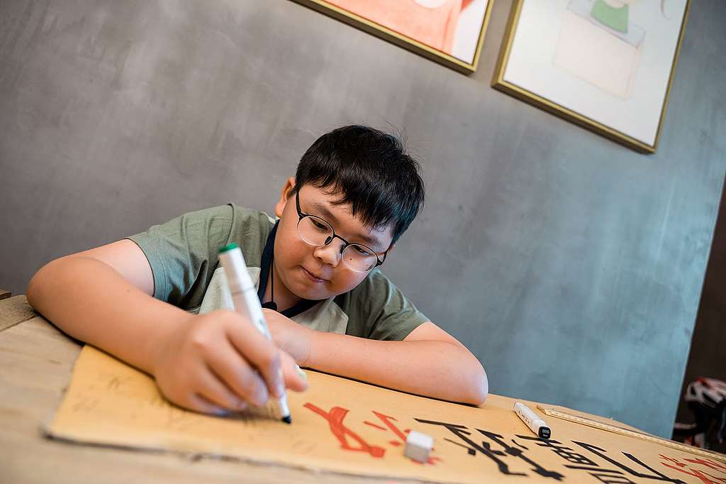 Lance製作氣候標語，計算紙板的長度、標語字數，然後作美術發揮。正正是糅合他對視藝和科學的喜好。© Patrick Cho/Greenpeace