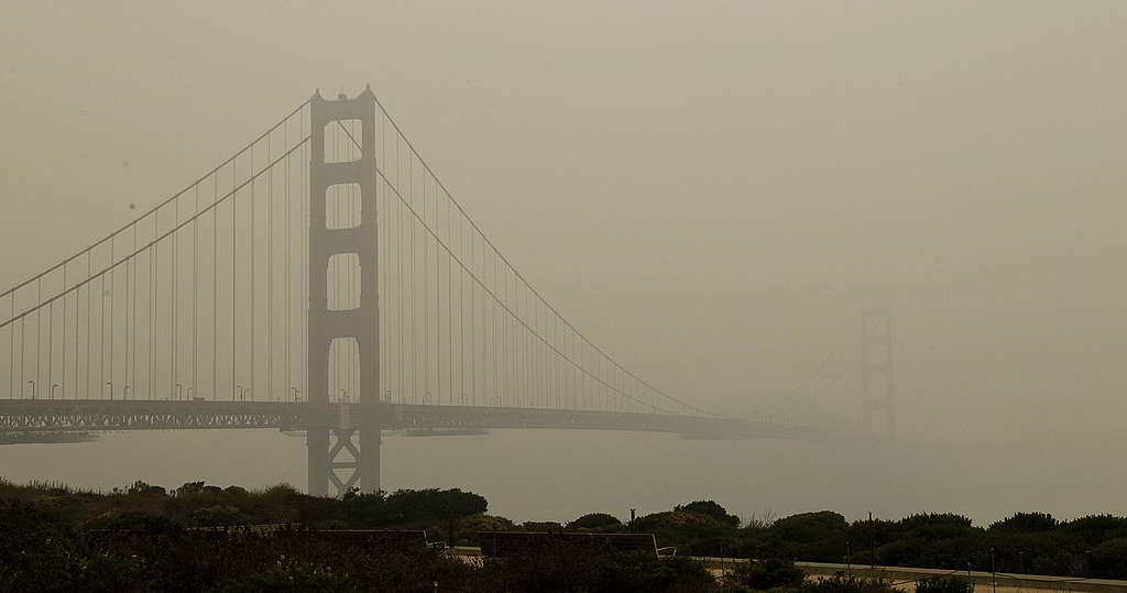 美國三藩市金門大橋的背景色從橙紅換上灰黃，代表當地居民續受煙霧與山火灰濃罩。 © George Nikitin / Greenpeace