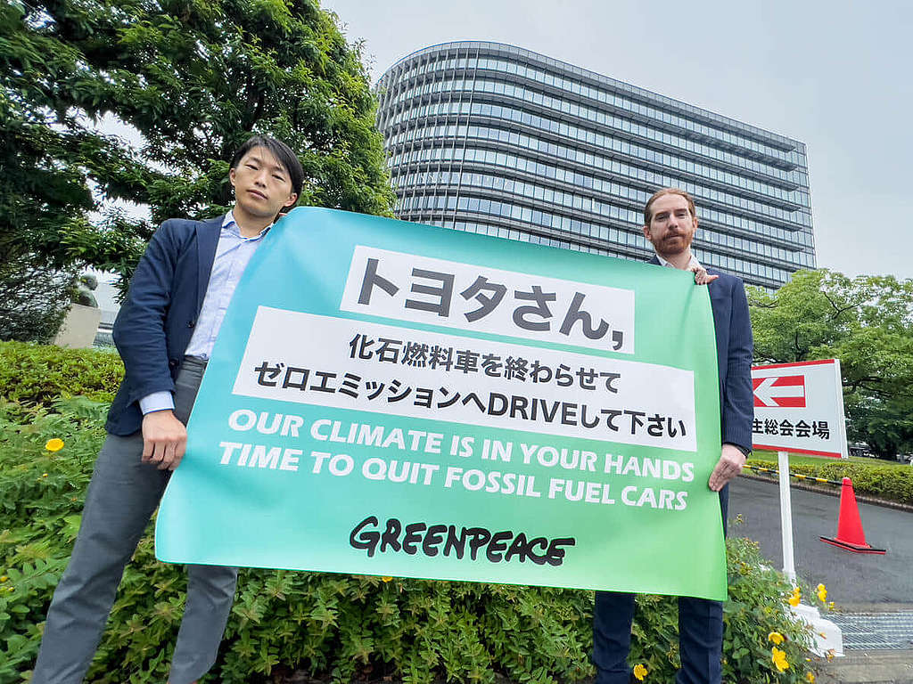 2022 年 6 月，綠色和平東京辦公室代表於豐田汽車的年度股東大會會場外舉起橫額，促請這間全球最大汽車生產商加快電動車轉型。 © Taishi Takahashi / Greenpeace