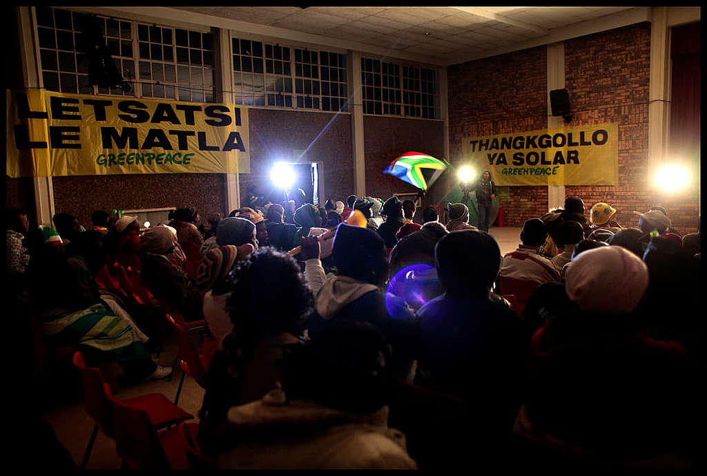 2010 年世界盃，綠色和平非洲辦公室在主辦國南非 Jericho 村落發起太陽能發電項目，幫助當地居民解決能源不穩問題，透過大螢幕一起為愛隊打氣。 © Benedicte Kurzen / Greenpeace