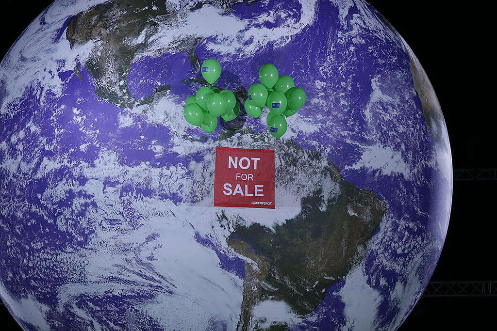 去年 COP26 會議結束前夕，綠色和平行動者於會場內徐徐升起「地球不是非賣品」橫額，促請各國領袖優先保障人民與環境福祉。 © Emily Macinnes / Greenpeace
