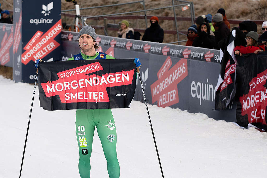 越野滑雪選手 Emil Johansson Kringstad 於一場 Equinor 冠名贊助的滑雪賽衝線時，展示「明日融化中」（MORGENDAGEN SMELTER）標語，控訴這間挪威國營石油企業的「漂綠」行為。 © Marthe Haarstad / Greenpeace