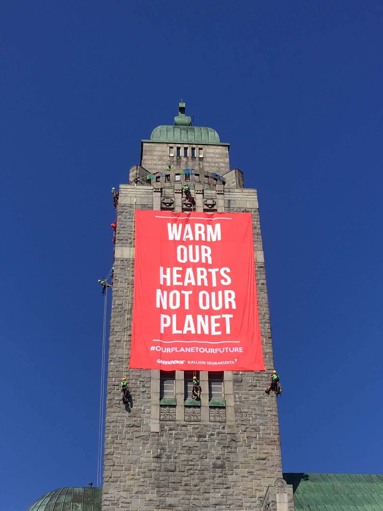 Greenpeace Nordic activists unfold two large banners in the high bell tower of Kallio church in Helsinki. © Greenpeace