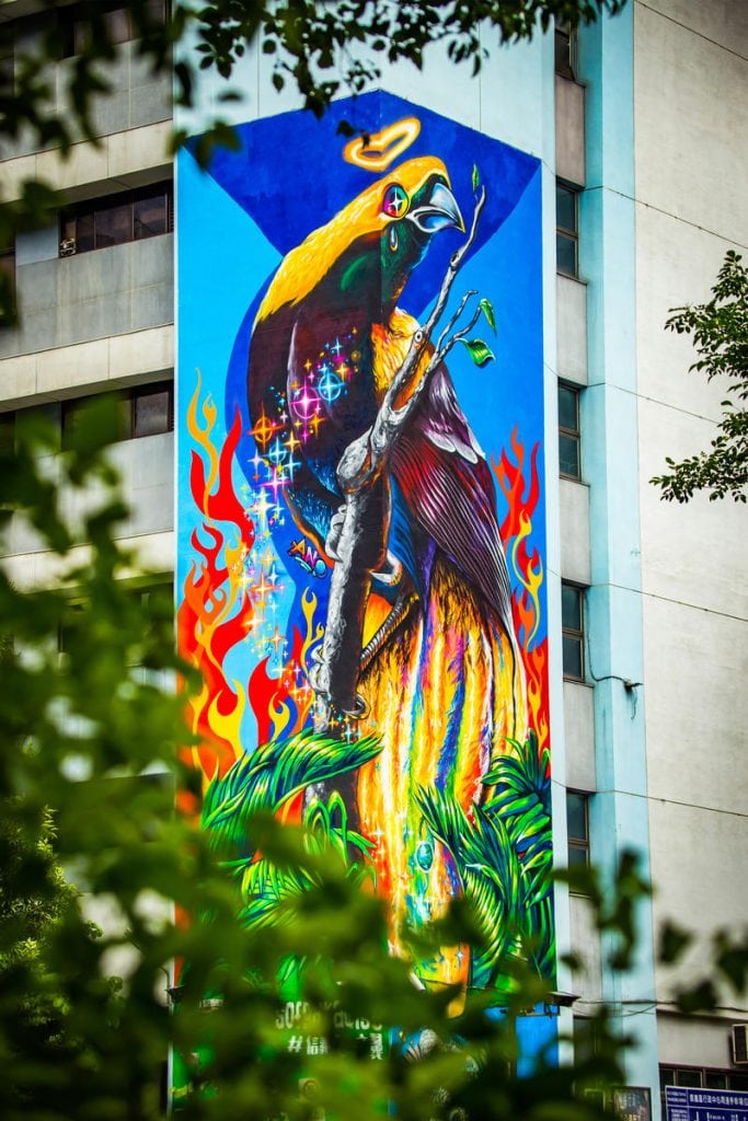 Street artist Ano paints a mural depicting birds of paradise close to Taipei 101, in the centre of the city. © Hong-Chi Huang / Greenpeace