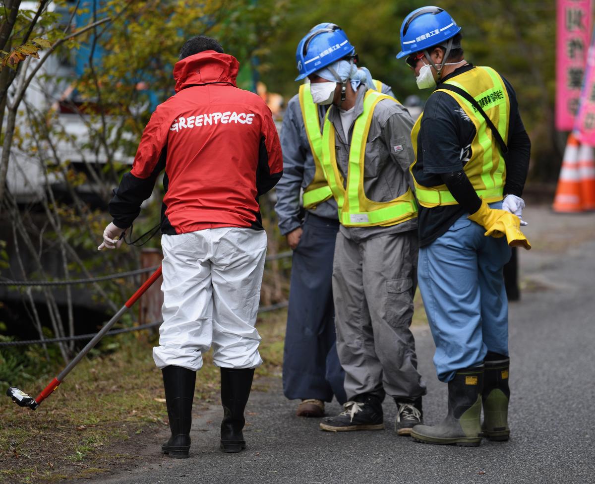 Workers and Greenpeace radiation specialist, Ray Lei, Obori, inside the Namie exclusion zone, Fukushima prefecture. © Shaun Burnie
