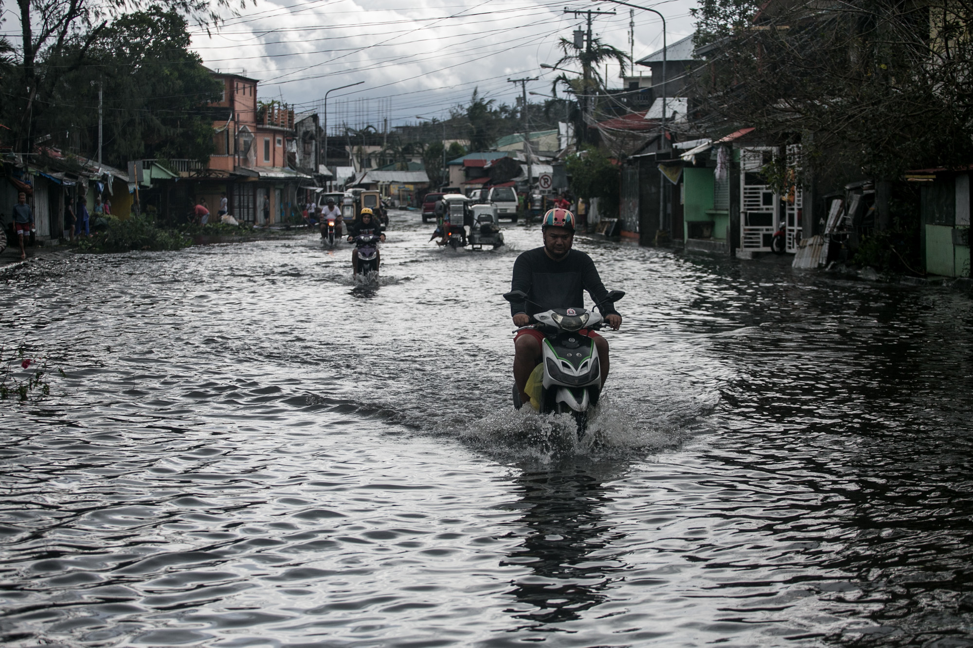 Motorists wade through a flooded street in the Philippines after Typhoon Tisoy