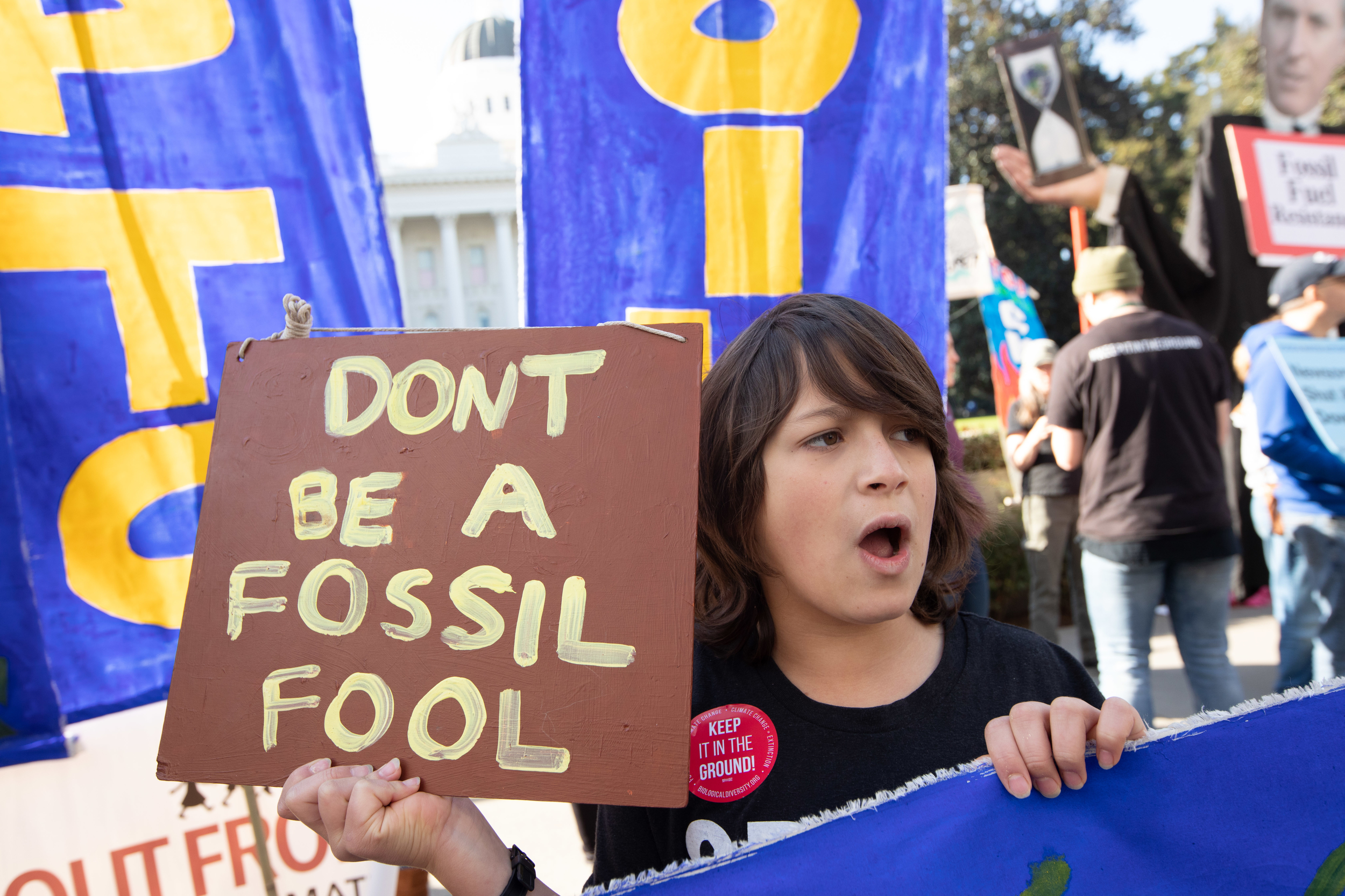 Woman taking part to California climate demonstration holding sign reading 'don't be a fossil fuel'