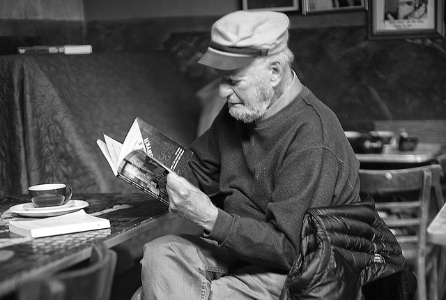 Poet Lawrence Ferlinghetti sits reading a paperback book at Caffe Trieste in 2012. Photo by Cmichel67 / Wikimedia Commons (CC BY-SA 4.0)