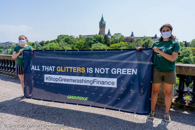 Greenpeace activists hold a banner that reads: 'All that glitters is not green - #StopGreenwashingFinance'. © Sara Poza Alvarez / Greenpeace