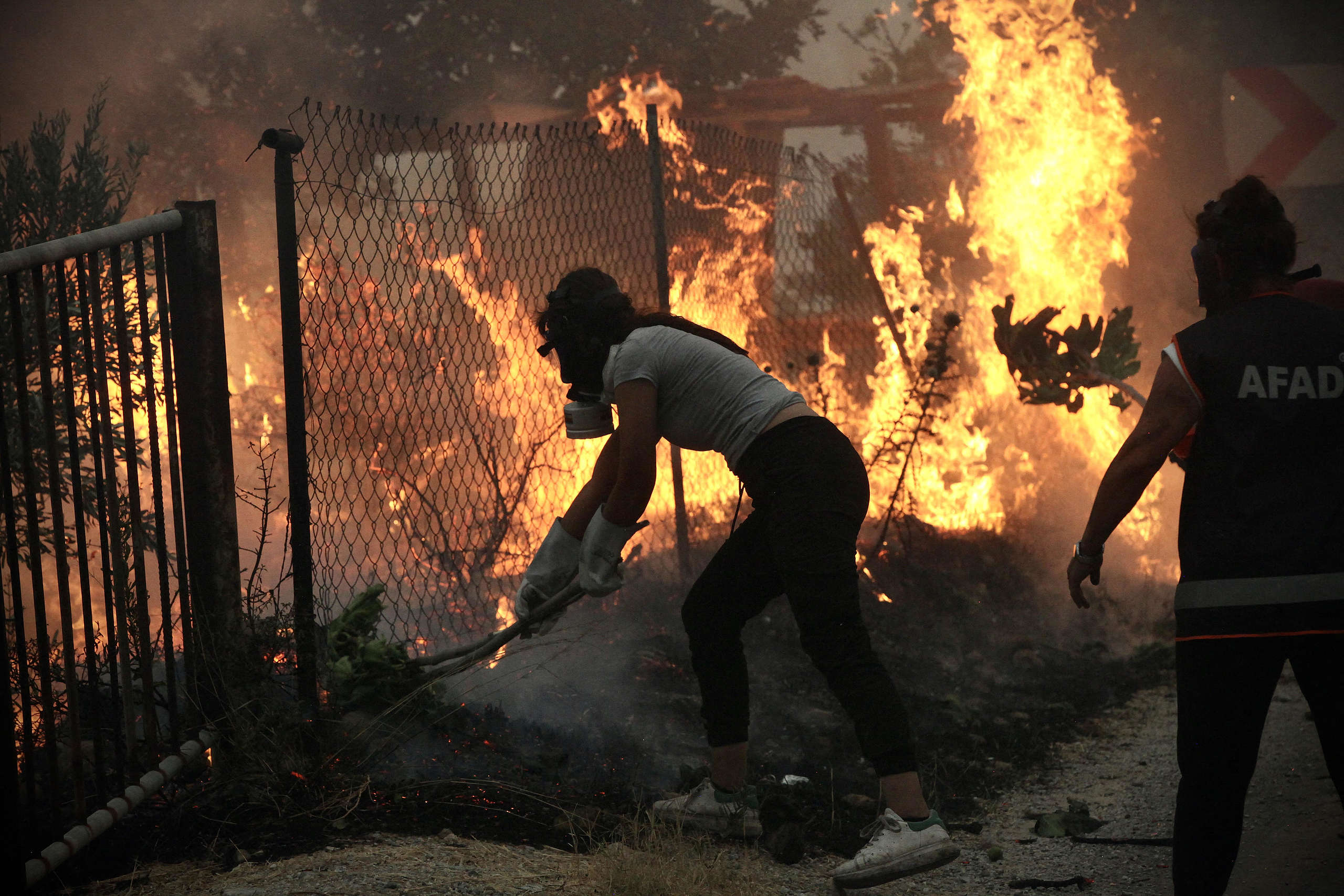 Inhabitants use branches to put out a fire spreading in the Aegean coast city of Oren, Turkey.