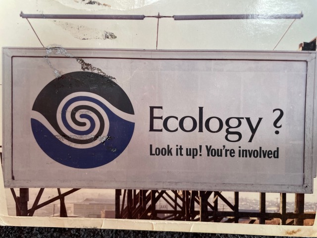 Image of a billboard with message "Ecology? Look it up! You're involved." These billboards were placed around Vancouver in 1970.