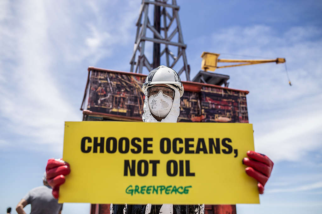 A protester holds a banner that read: "Choose Oceans, Not Oil."© Gabriel Bulacio / Greenpeace