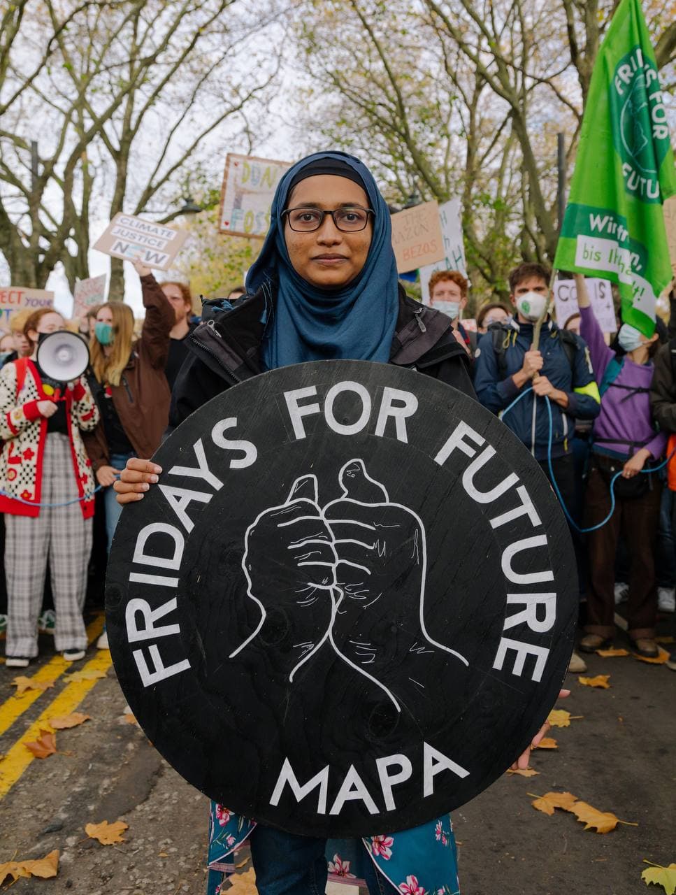 A girl wearing a head scarf holding a placard that says Fridays For Future MAPA. Behind her are other young people at the strike.