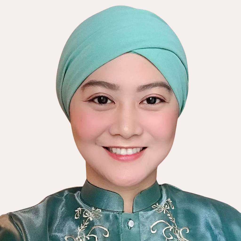A girl wearing a green head covering smiling at the camera