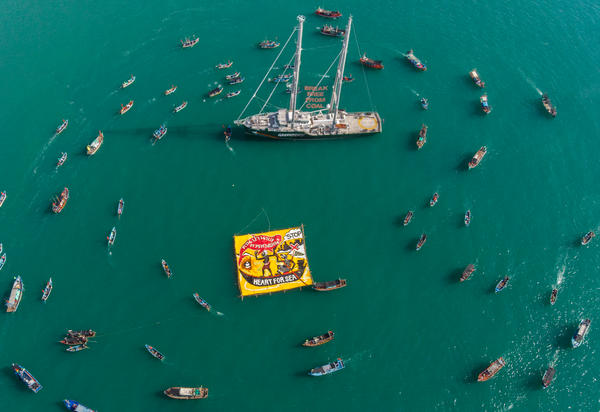 Boats including the Rainbow Warrior protest in a doughnut shape in Teluk Patani, Thailand, against a coal-fired project, demanding 100% Renewable Energy for All.